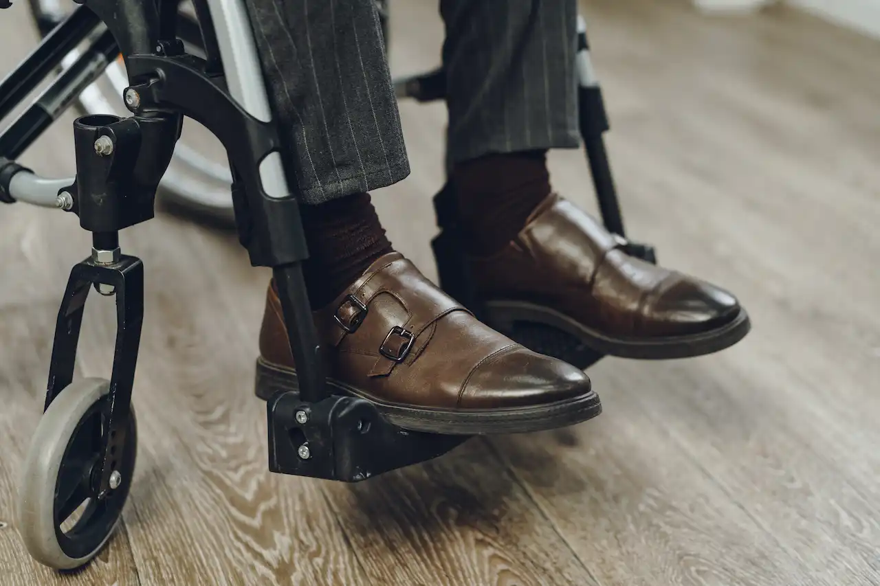 A detail photo of wheelchair seated feet wearing dress shoes.